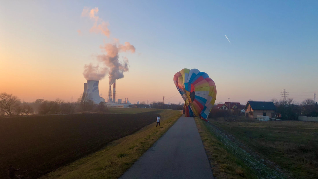 Balon na ogrzane powietrze unoszący się nad Wisłą o zmierzchu, widziany z nadwiślańskiej ścieżki rowerowej.